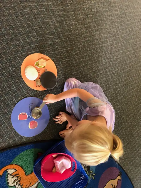 A child sorting rough and smooth materials on the rug
