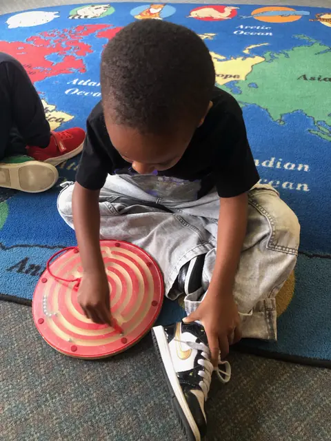 A child tracing a wooden maze