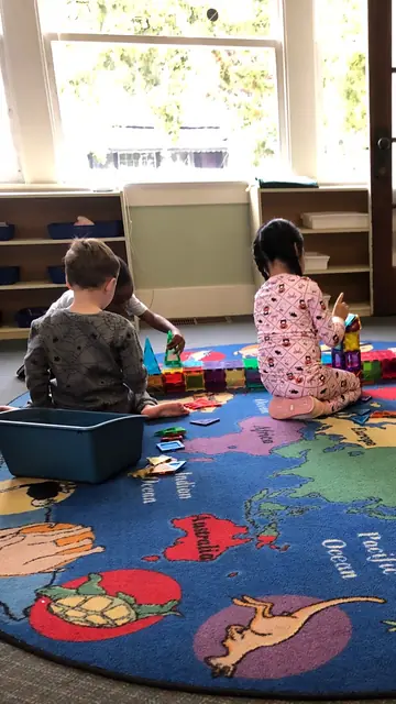 Children building with magnetic tiles by the window